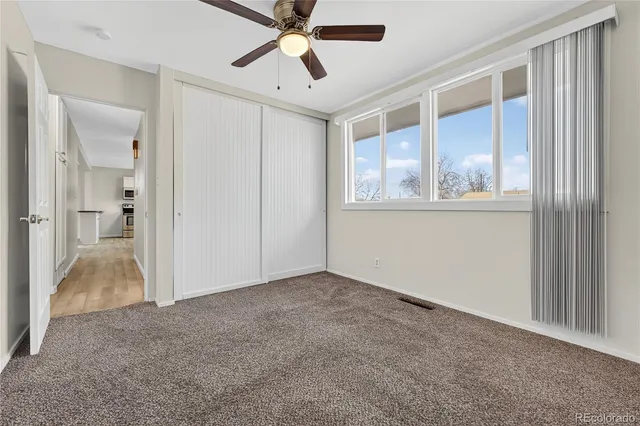 an empty room with windows and ceiling fan