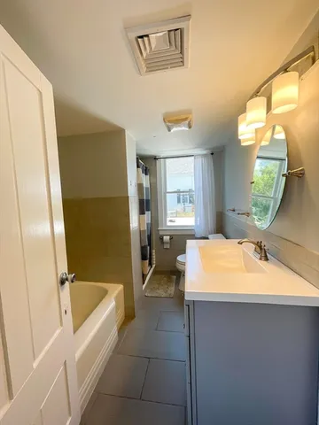 a bathroom with a tub sink and mirror