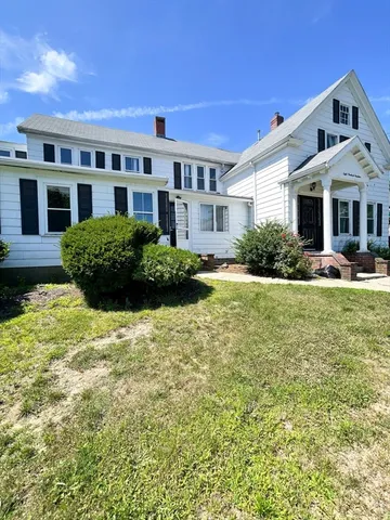 a front view of a building with garden and trees