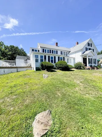 a view of a house with a big yard and large trees