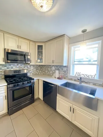 a kitchen with kitchen island granite countertop a stove a sink and a microwave