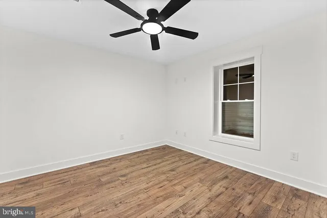 an empty room with a window and a fan