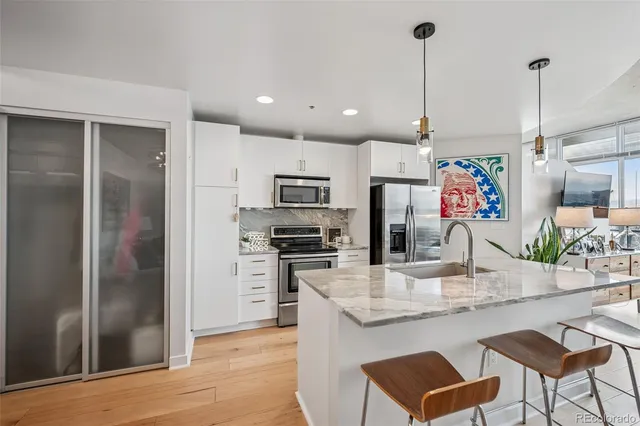 a kitchen with stainless steel appliances granite countertop a refrigerator a stove and a sink