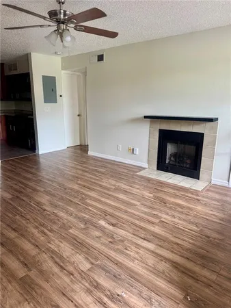 an empty room with wooden floor a ceiling fan a fireplace and windows