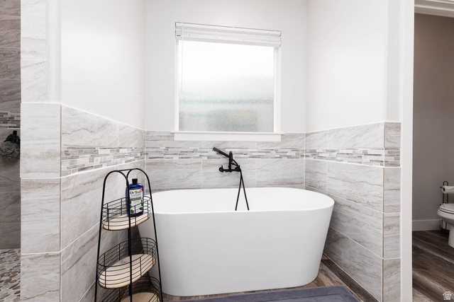 186 West 580 North Redmond, UT 84652 - Photo 27 of 74 Bathroom featuring tile walls, a freestanding bath, wainscoting, and wood finished floors