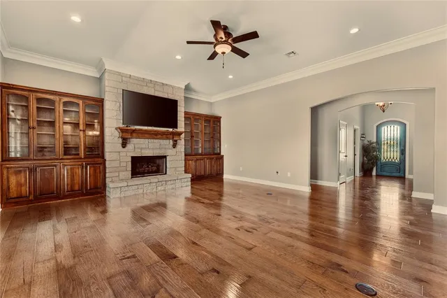 a view of a livingroom with furniture a flat screen tv wooden floor and a ceiling fan