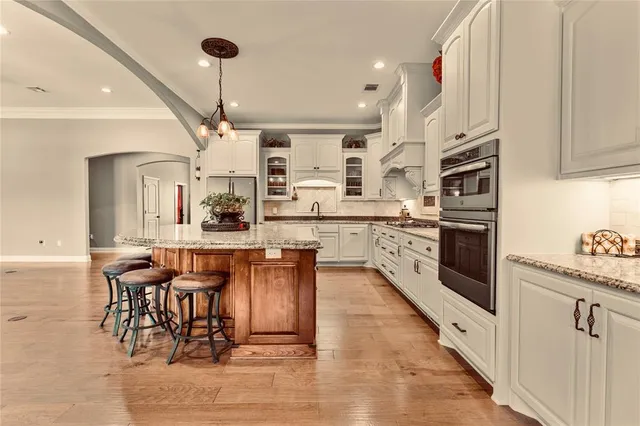 a kitchen with stainless steel appliances kitchen island granite countertop a table chairs and a refrigerator