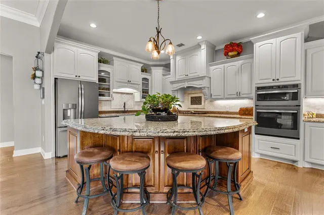 a kitchen with stainless steel appliances granite countertop a table chairs stove and refrigerator