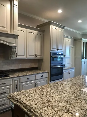 a kitchen with kitchen island granite countertop a stove and cabinets
