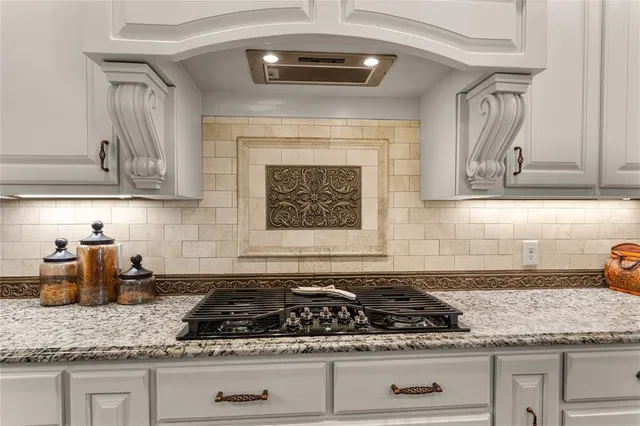 a kitchen with granite countertop stainless steel appliances stove top oven and cabinets