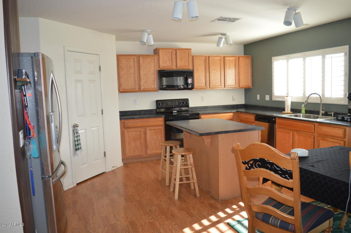 4351 East Pinto Valley Road San Tan Valley, AZ 85143 - Photo 4 of 27 a kitchen with stainless steel appliances granite countertop a refrigerator a sink dishwasher a stove a dining table and chairs with wooden floor