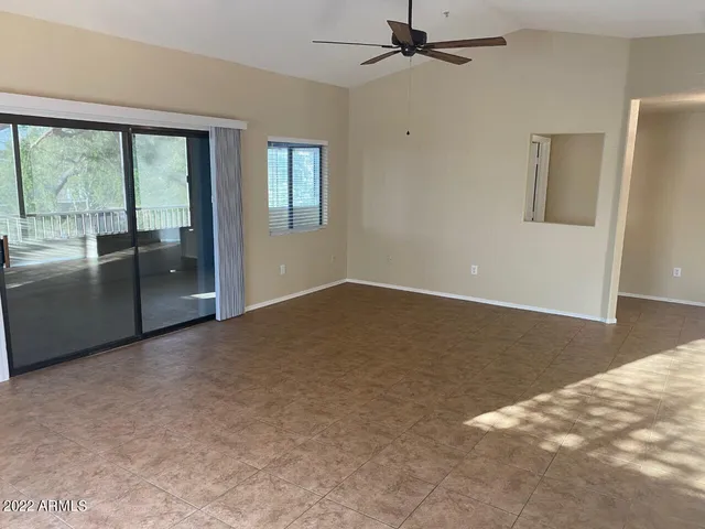 an empty room with chandelier fan and windows