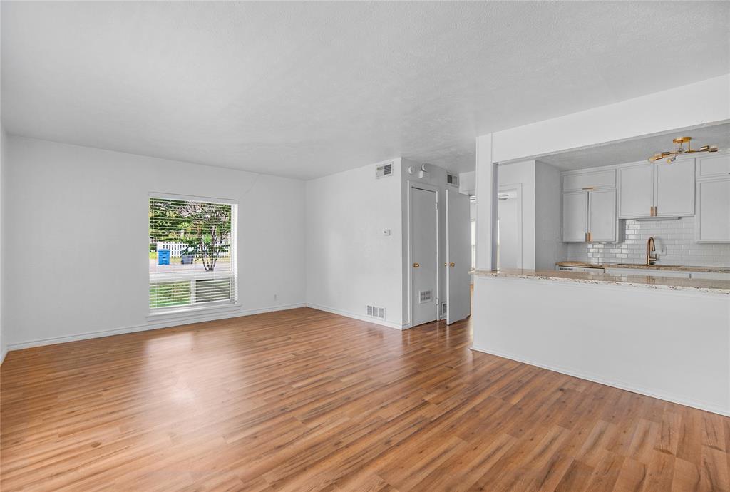 4723 Victor Street, Unit B Dallas, TX 75246 - Photo 2 of 12 Spacious room featuring wood-finish flooring, white walls, and a large window with blinds