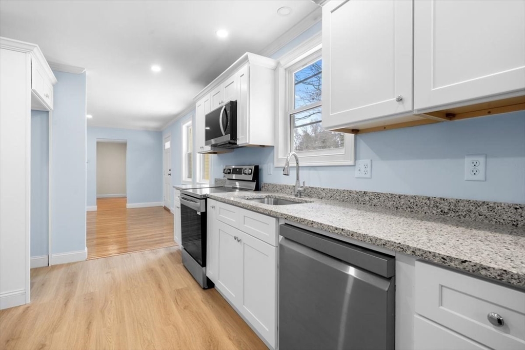 36 Grove Street Hanover, MA 02339 - Photo 5 of 25 a kitchen with granite countertop a sink and dishwasher a stove top oven with wooden floor