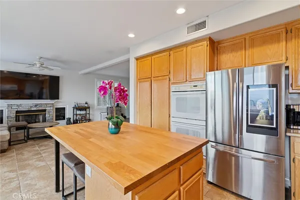 a kitchen with stainless steel appliances kitchen island granite countertop a refrigerator a stove top oven a dining table and chairs with wooden floor