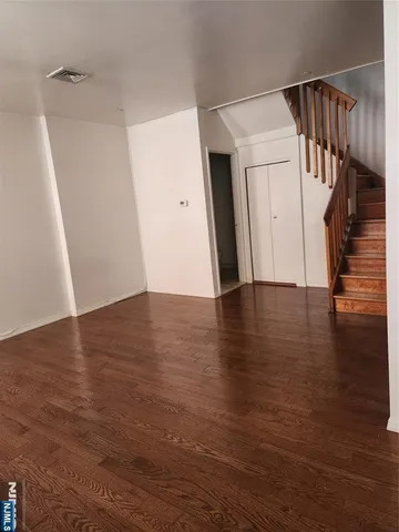 a view of an empty room with wooden floor and stairs
