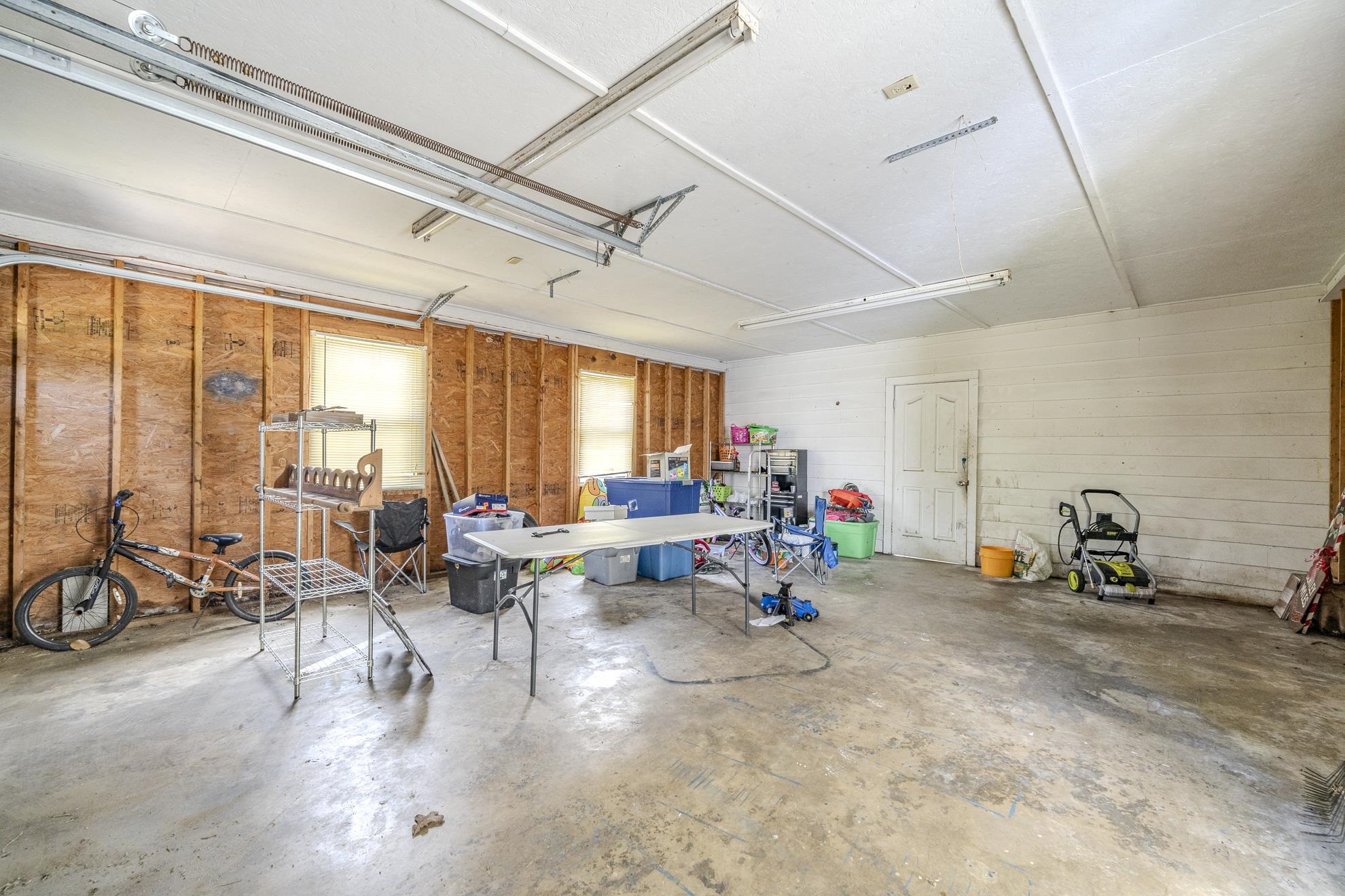 369 Bethel-Purdy Road Bethel Springs, TN 38315 - Photo 19 of 19 Spacious garage featuring a concrete floor, two windows providing natural light, exposed wood framing on one wall, and white shiplap on another
