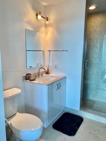 a bathroom with a sink a toilet a mirror and shower