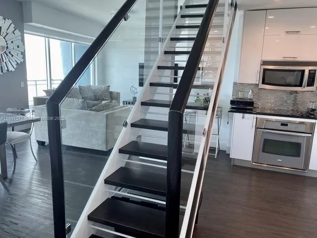 a view of an empty room with wooden floor and stairs