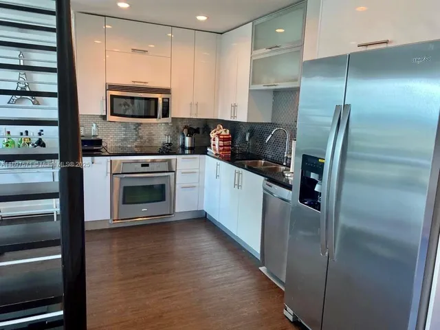a kitchen with stainless steel appliances granite countertop a refrigerator a stove and a sink