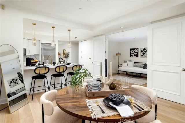 a kitchen with stainless steel appliances granite countertop a sink a stove a refrigerator and chairs with wooden floor