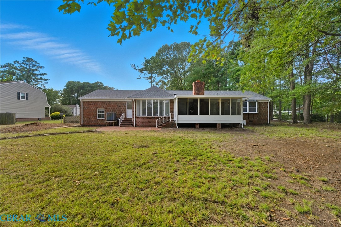 718 Dandy Loop Road Yorktown, VA 23692 - Photo 32 of 42 Rear view of house featuring a sunroom, a chimney, a lawn, and brick siding