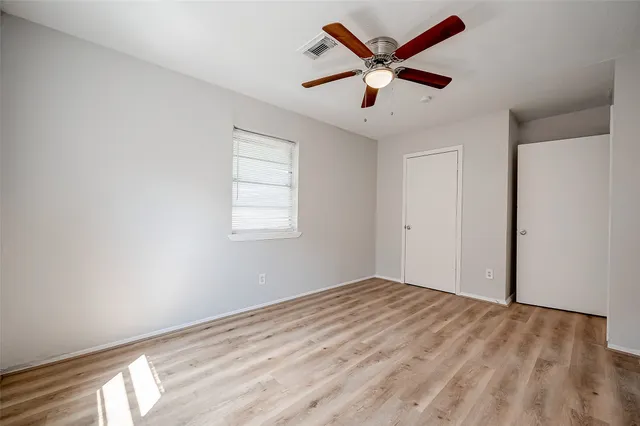an empty room with wooden floor and ceiling fan