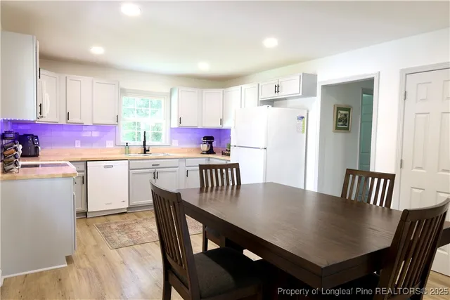 a kitchen with a dining table chairs and white cabinets