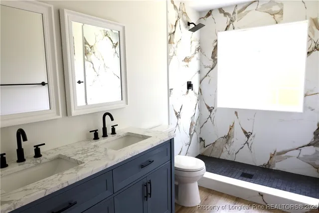 a bathroom with a granite countertop sink mirror vanity and toilet