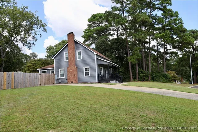 a front view of house with yard and trees all around