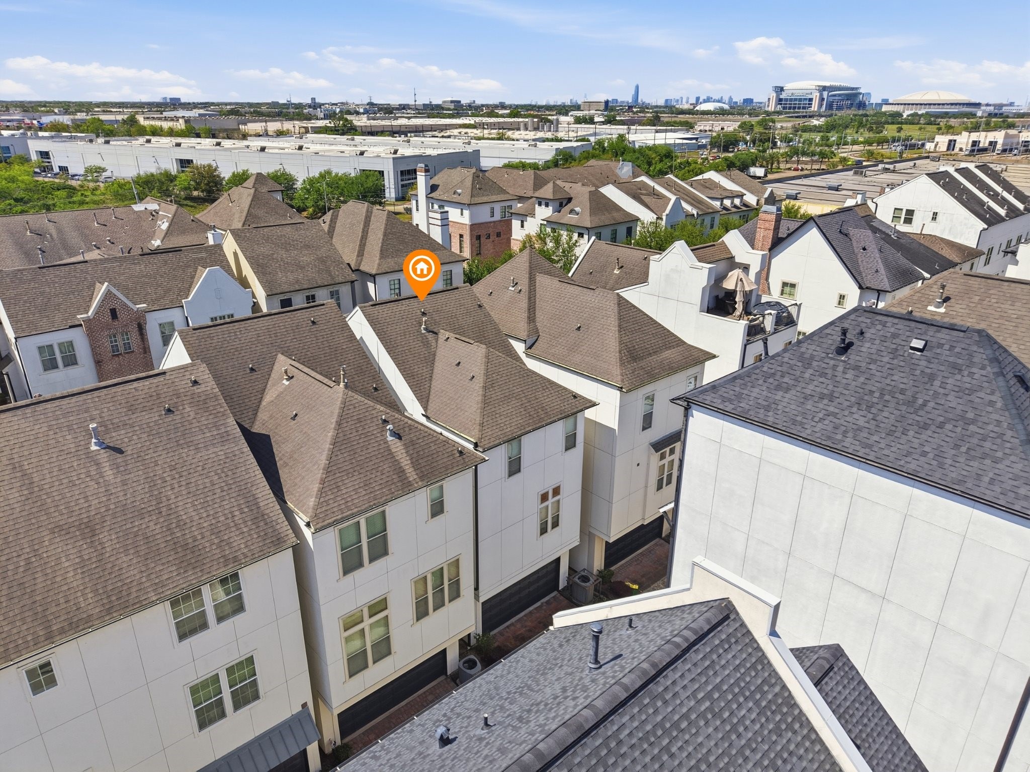 9427 London Bridge Station Houston, TX 77045 - Photo 26 of 30 This photo shows a cluster of modern townhouses with uniform roofs in a suburban setting. The area is densely packed, with the homes featuring large windows and contemporary designs. Nearby amenities and cityscape views are visible in the background, indicating a well-connected neighborhood.