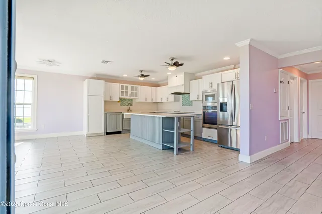 a kitchen with stainless steel appliances kitchen island granite countertop a refrigerator and a sink