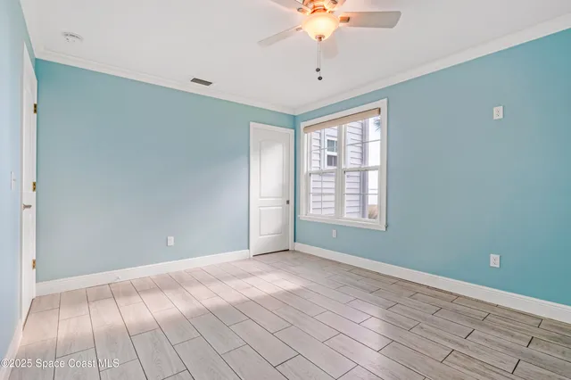 a view of an empty room with window and chandelier fan