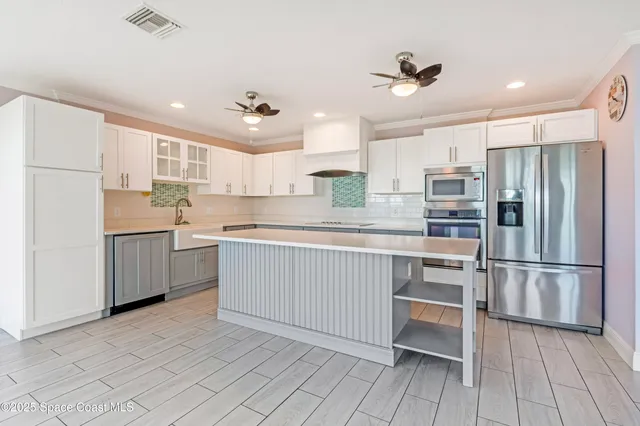 a kitchen with kitchen island white cabinets and stainless steel appliances