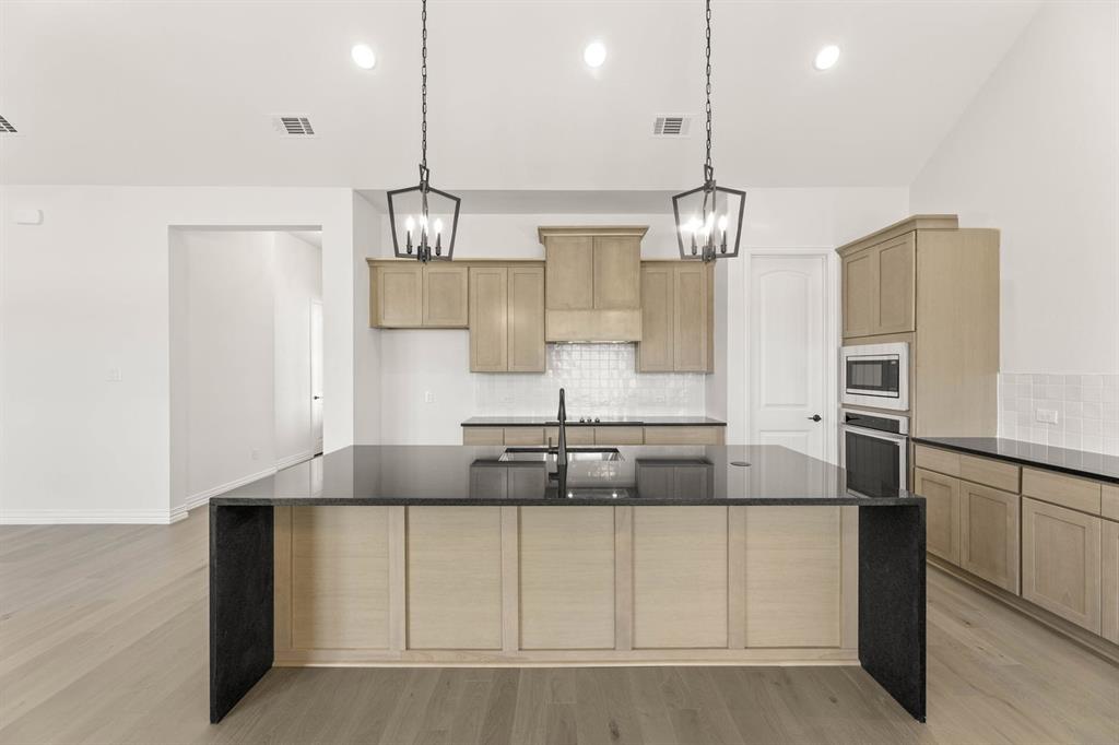 317 Slimp Bluff Azle, TX 76020 - Photo 11 of 25 a kitchen with kitchen island granite countertop stainless steel appliances and a chandelier