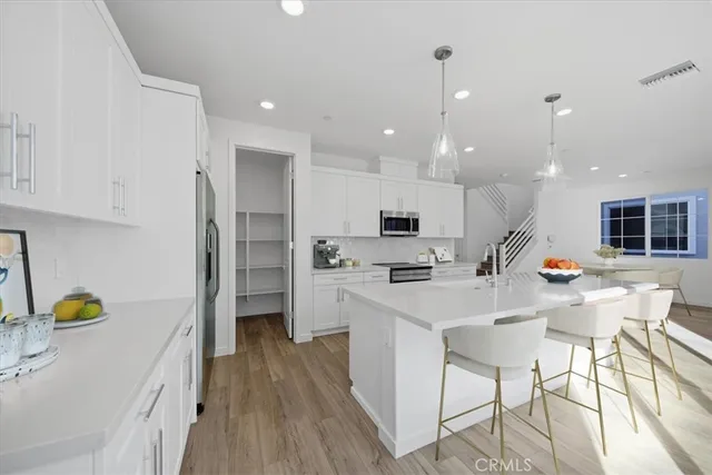 a kitchen with stainless steel appliances a stove a sink a refrigerator white cabinets and wooden floor