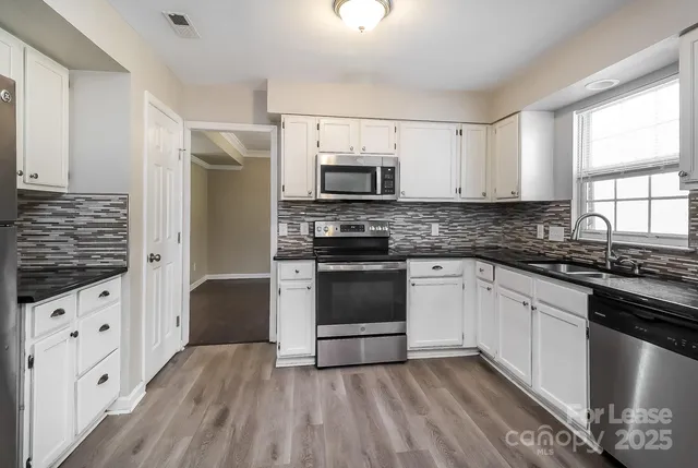 a kitchen with granite countertop a stove a sink and a refrigerator