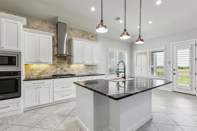 a kitchen with granite countertop white cabinets and sink