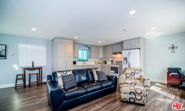 a view of kitchen with stainless steel appliances granite countertop a couch and a dining table with wooden floor