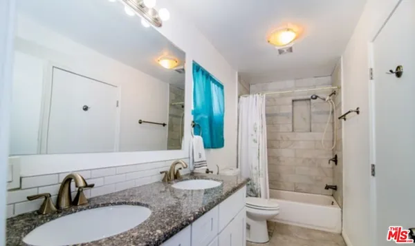 a bathroom with a granite countertop sink a toilet a mirror and shower