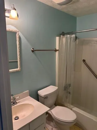 a white toilet sitting next to a bathroom sink and a shower