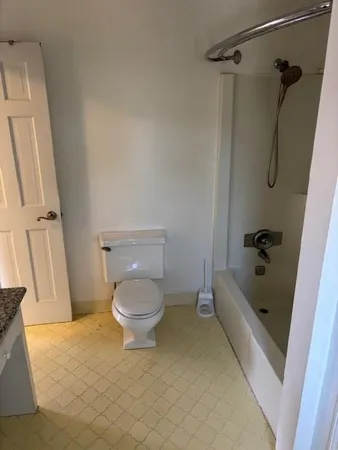 a bathroom with a granite countertop bathtub shower and toilet