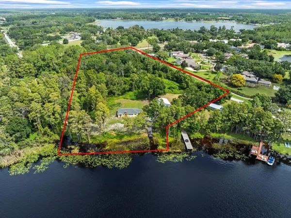 an aerial view of a houses with a yard and lake view