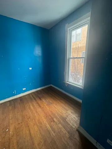 an empty room with wooden floor and a sink