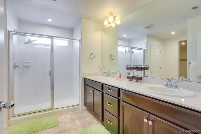 a bathroom with a double vanity sink mirror and shower