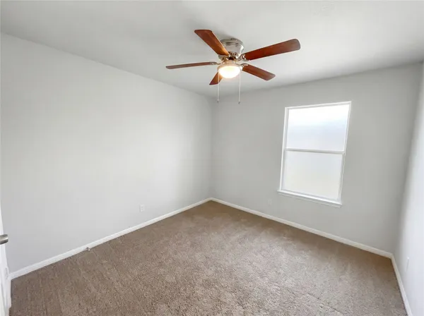 an empty room with a window and ceiling fan