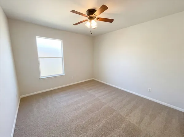 an empty room with a window and a ceiling fan