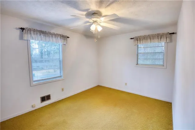 an empty room with a chandelier fan and windows