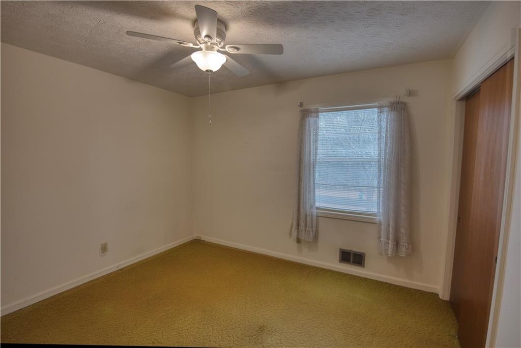 6100 Mincey Road Stone Mountain, GA 30087 - Photo 20 of 40 an empty room with a chandelier fan and windows
