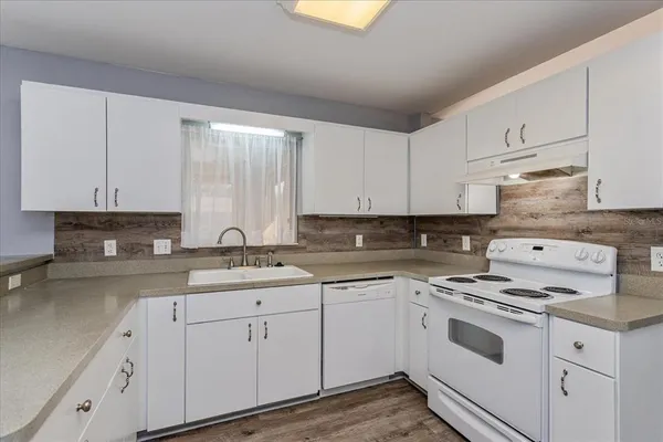 a kitchen with cabinets appliances a sink and a window